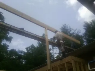 Carpenter setting a ridge beam over a new addition frame — Ice Dam Removal by Roofing Brothers in Flint
