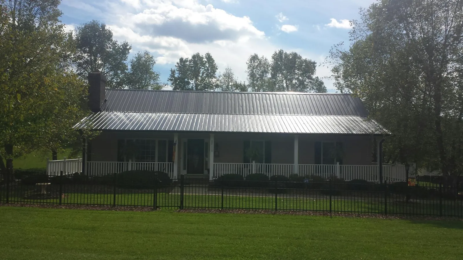 Gray metal roof on a brick ranch with a full width front porch — Gutter Guard Installation work by our crew in Flint